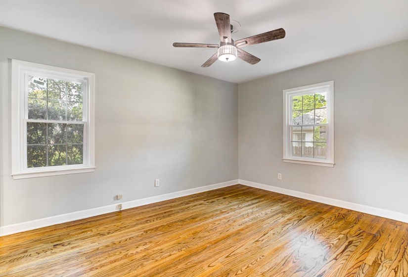 Bright room featuring wood-finish flooring, light gray wall paint, white trim, and a ceiling fan with integrated lighting