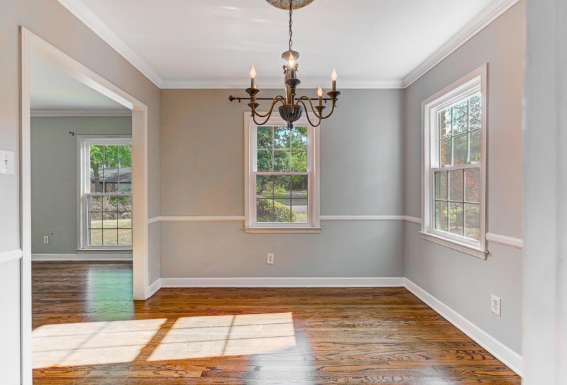 Dining Room with wood-finish flooring, two large windows, white crown molding, and wainscoting, beautiful light!