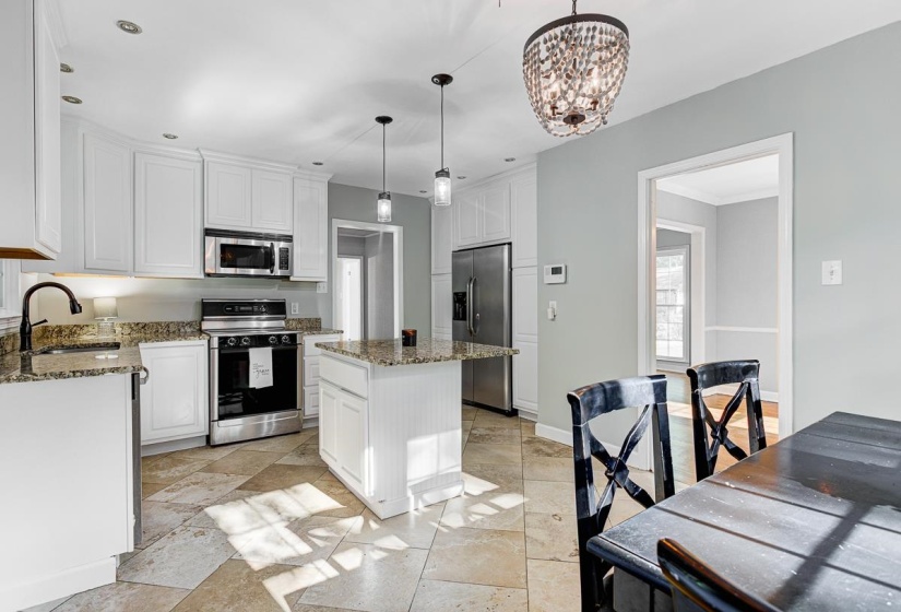 Kitchen featuring white cabinetry, stainless steel appliances, granite countertops, and a central island