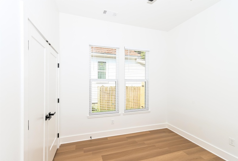 Room featuring wood-finish flooring, white baseboards, and bright white walls