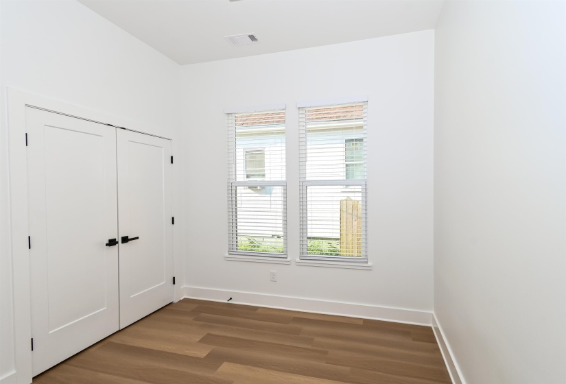 Bright interior room featuring wood-finish flooring, white walls, and a double window with blinds