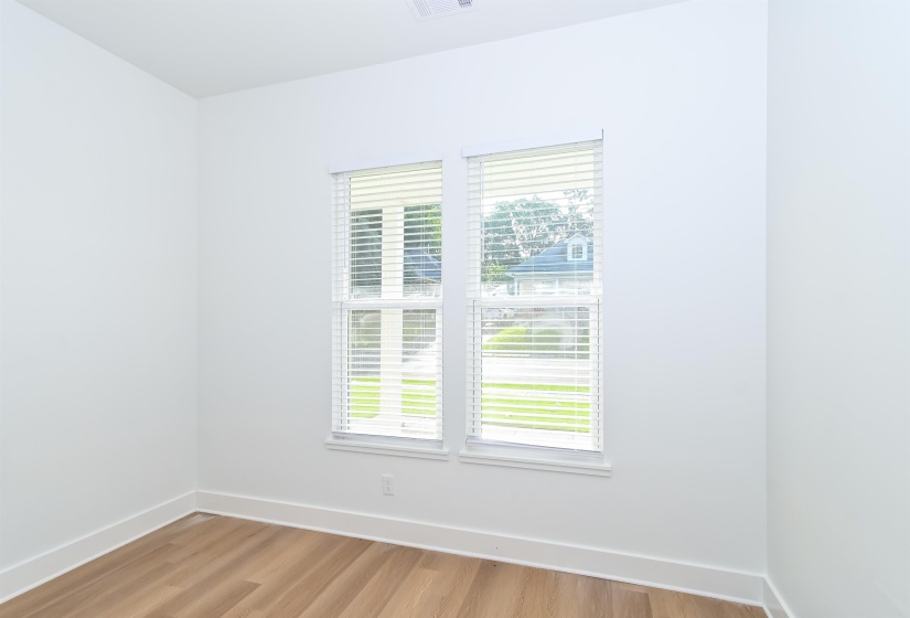 Dual windows with white blinds, wood-finish flooring, white walls, and white baseboards