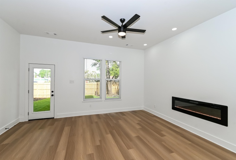 Spacious room featuring wood-finish flooring, a contemporary ceiling fan, and recessed lighting