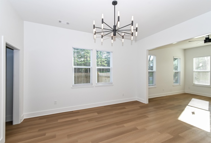 Spacious interior featuring wood-finish flooring, white walls, and a contemporary black chandelier