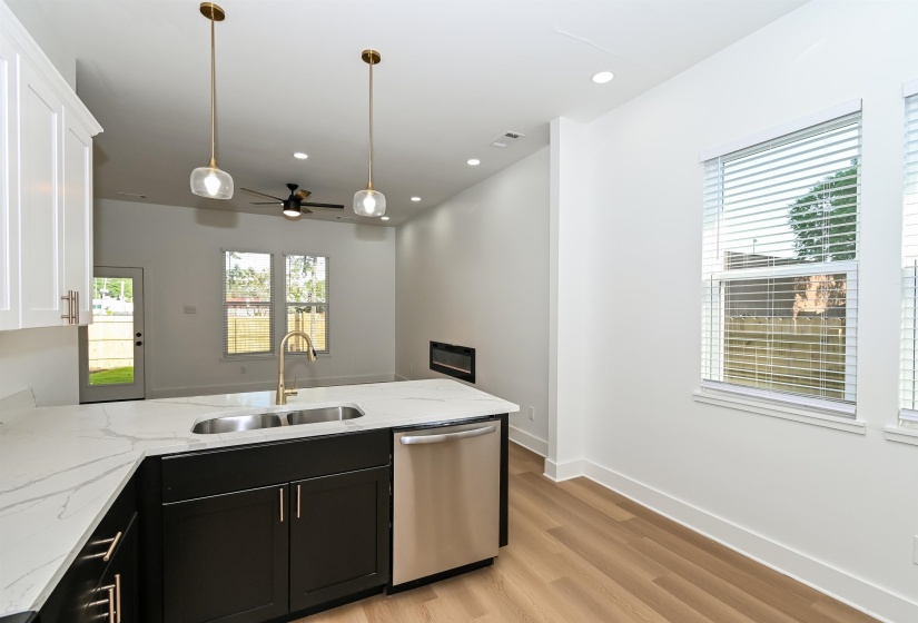 Modern kitchen featuring a large island with a double stainless steel sink, gold-finish faucet, and white quartz-finish countertop