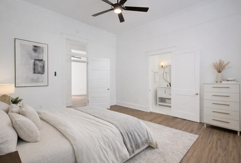 Bedroom with dark wood-style flooring, ensuite bath, crown molding, and a ceiling fan