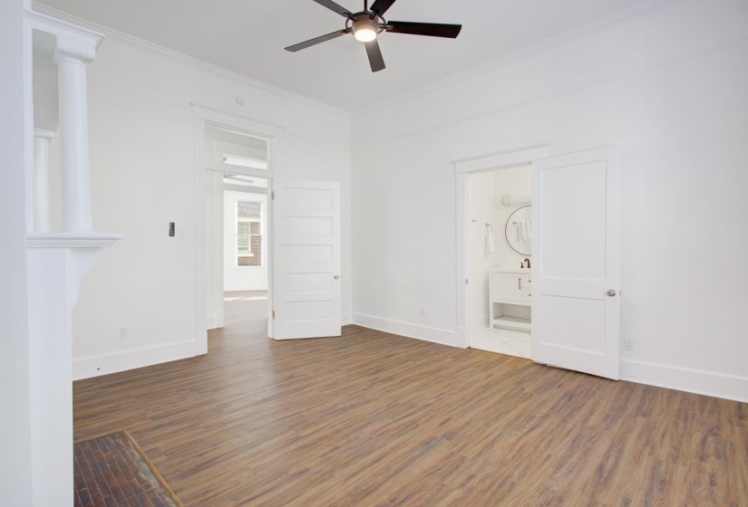 Unfurnished bedroom with dark wood-style floors, crown molding, connected bathroom, and ceiling fan