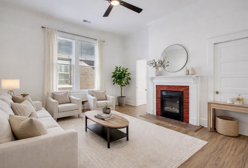 Living area featuring light wood finished floors, a ceiling fan, a fireplace, and ornamental molding