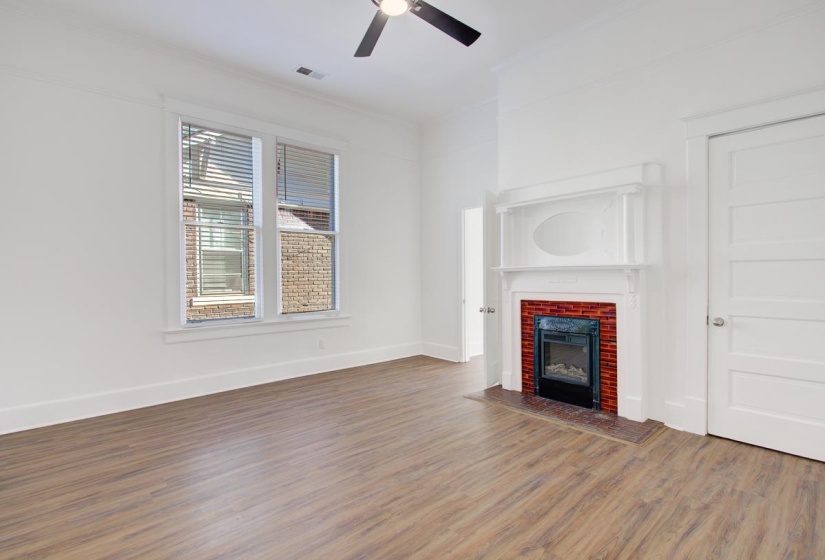 Unfurnished living room with wood finished floors, ornamental molding, a ceiling fan, and a fireplace