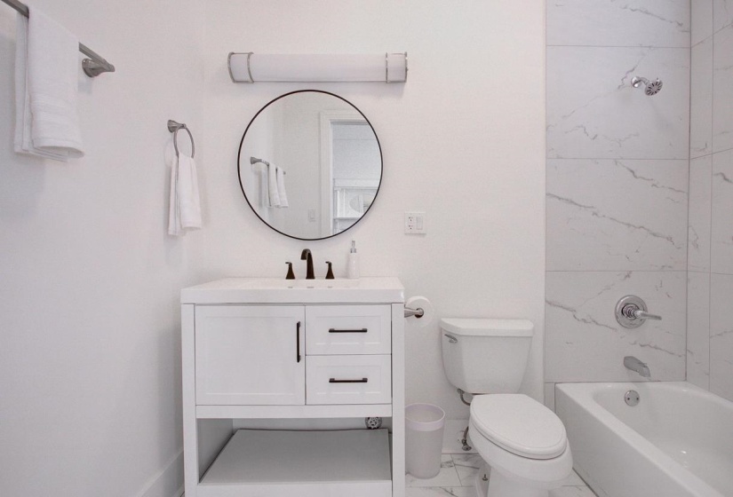 Full bath featuring vanity, tub / shower combination, and marble look tiles