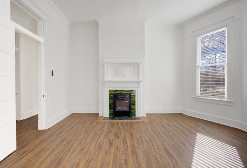 Unfurnished living room featuring ornamental molding, wood finished floors, and a tile fireplace