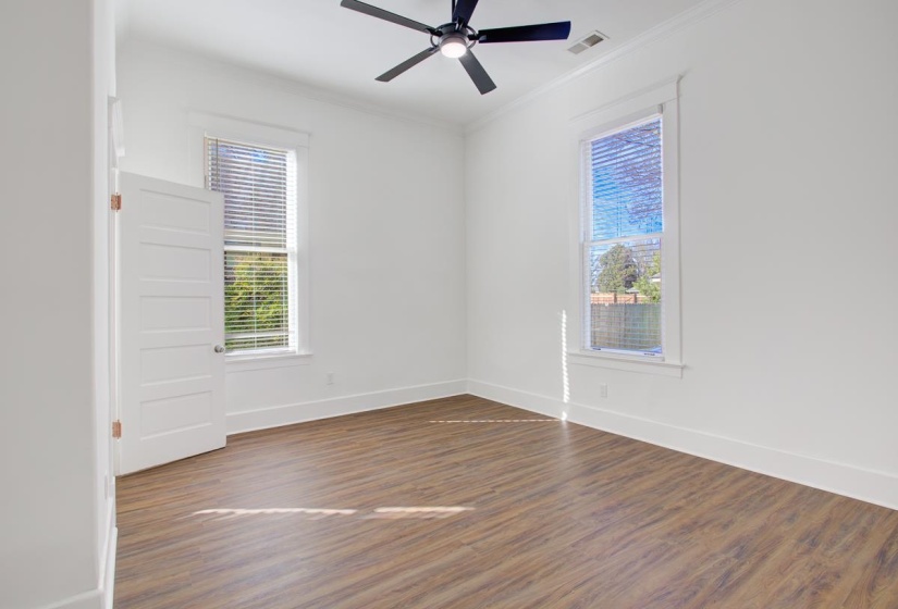 Empty room with dark wood-style floors, ornamental molding, and a ceiling fan