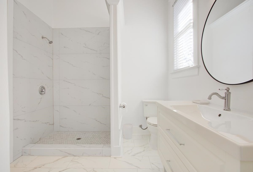 Bathroom with vanity, a marble finish shower, and light marble finish floors