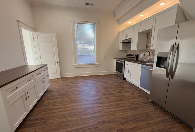 Kitchen with stainless steel appliances, crown molding, dark wood-style floors, tasteful backsplash, and recessed lighting