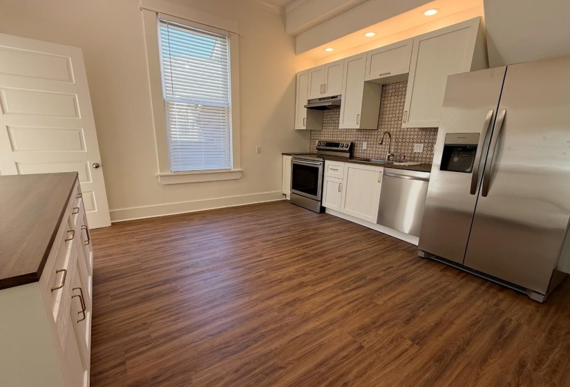 Kitchen with stainless steel appliances, dark countertops, dark wood-style flooring, ornamental molding, and recessed lighting