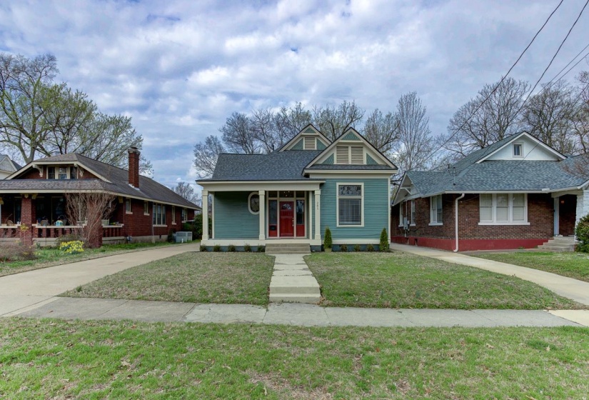 View of front facade with covered porch, a front yard, and a shingled roof