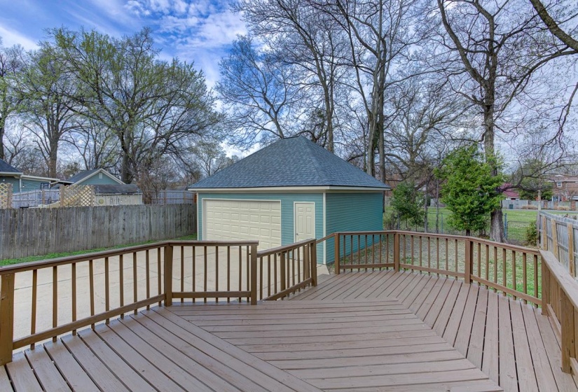 Wooden terrace featuring an outdoor structure, a fenced backyard, and a detached garage