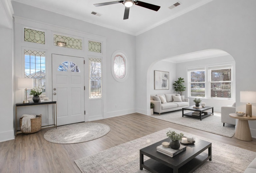 Foyer entrance featuring ornamental molding, wood finished floors, ceiling fan, arched walkways, and a high ceiling