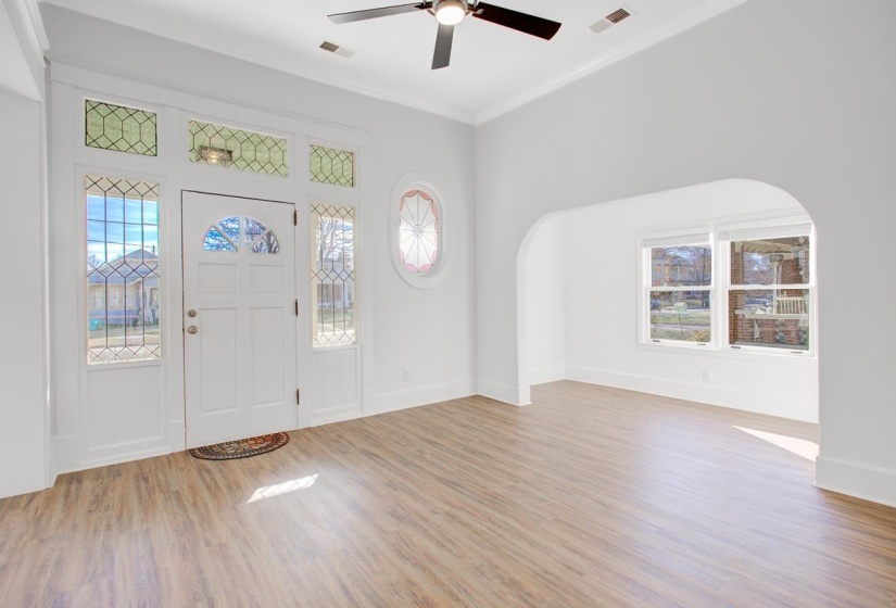 Entrance foyer featuring light wood-style flooring, ornamental molding, ceiling fan, and plenty of natural light