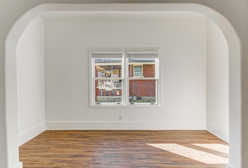 Unfurnished room featuring arched walkways and wood finished floors