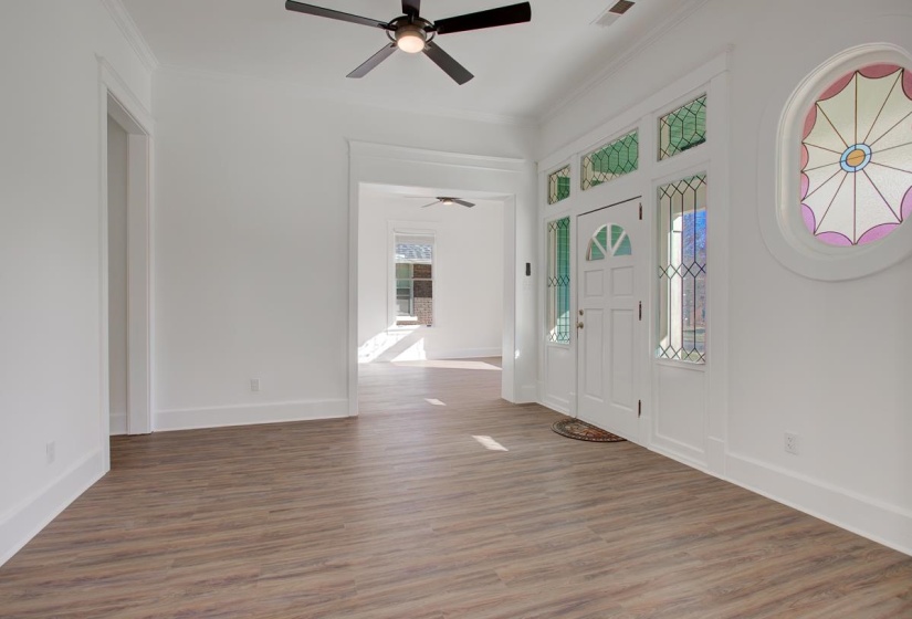 Entrance foyer featuring light wood finished floors, a ceiling fan, and crown molding