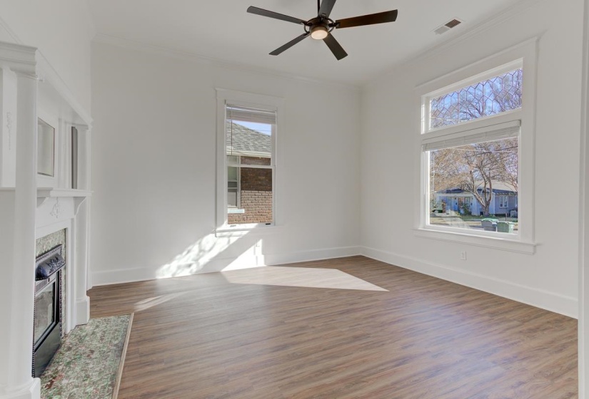 Unfurnished living room with crown molding, dark wood-style flooring, ceiling fan, and a glass covered fireplace