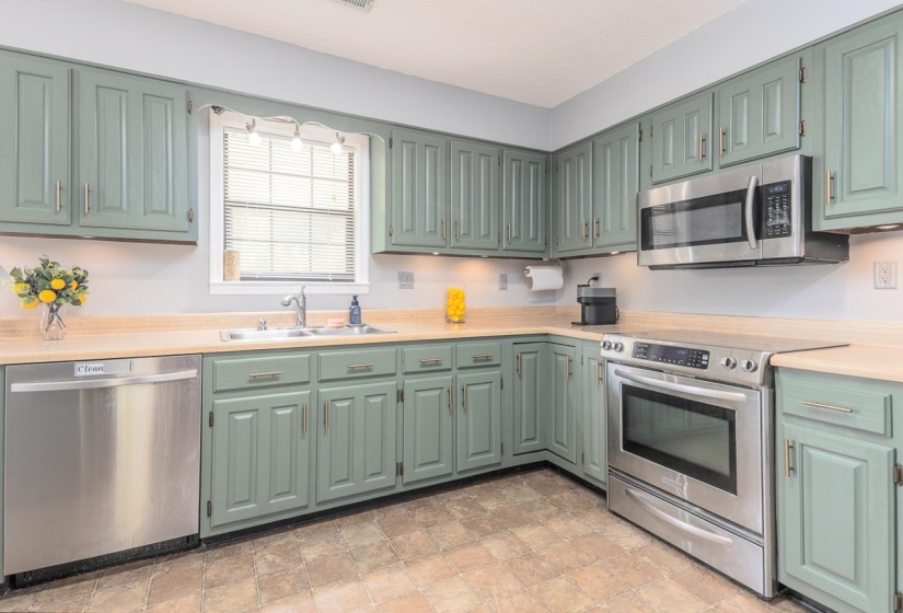 Kitchen featuring appliances with stainless steel finishes, light countertops, and green cabinets