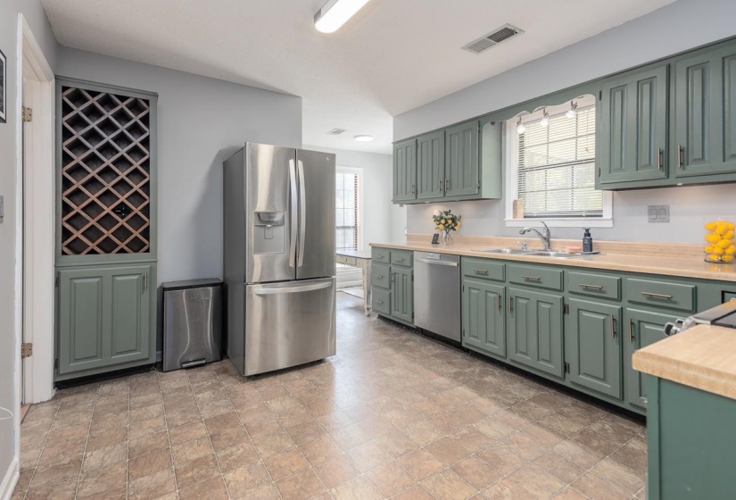 Kitchen with green cabinetry, light countertops, stainless steel appliances, and plenty of natural light