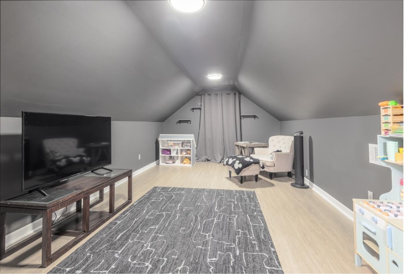 Currently being used as a bonus room with vaulted ceiling and light wood-type flooring