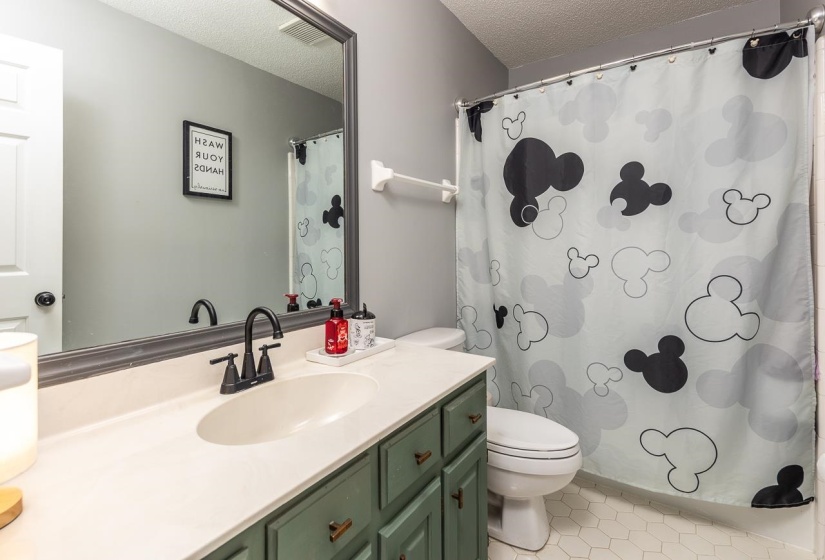 Full bathroom featuring vanity, a textured ceiling, light tile patterned floors, and curtained shower