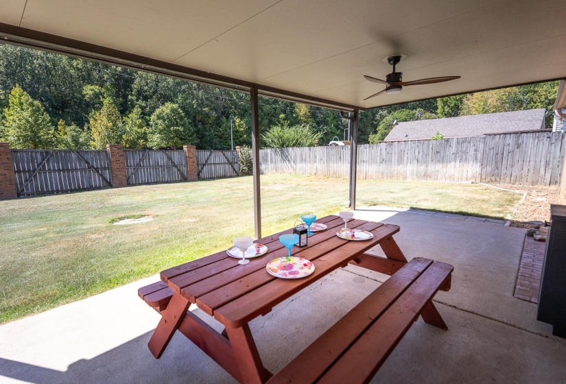 Fenced backyard with a ceiling fan, a patio area, and outdoor dining area