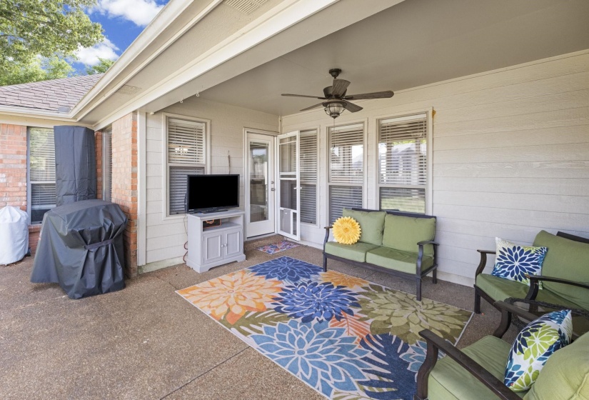 Covered patio featuring a ceiling fan, concrete flooring, and an exterior door with side windows