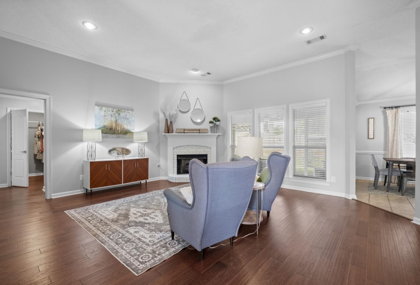 Spacious living area featuring wood-finish flooring and a corner fireplace with a white mantel and tile surround