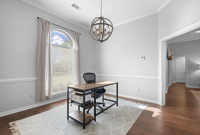 Versatile room featuring an arched window, crown molding, and wainscoting