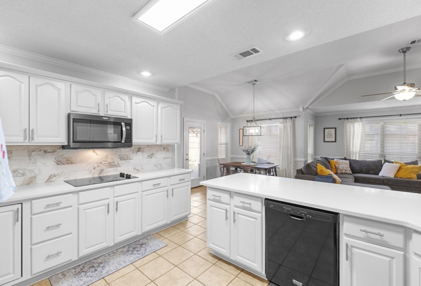 Kitchen featuring white cabinetry, light countertops, a built-in microwave, and a black stovetop