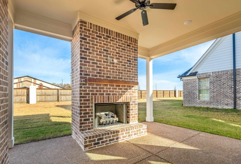 View of patio with an outdoor brick fireplace and a ceiling fan