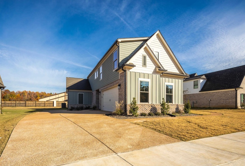 View of front of property with board and batten siding, brick siding, concrete driveway, and an attached garage