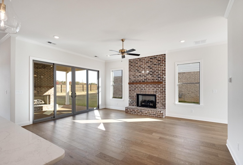 Unfurnished living room with crown molding, hardwood / wood-style floors, ceiling fan, a fireplace, and recessed lighting