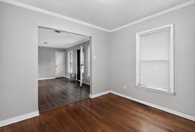 Unfurnished room with crown molding and dark wood-type flooring