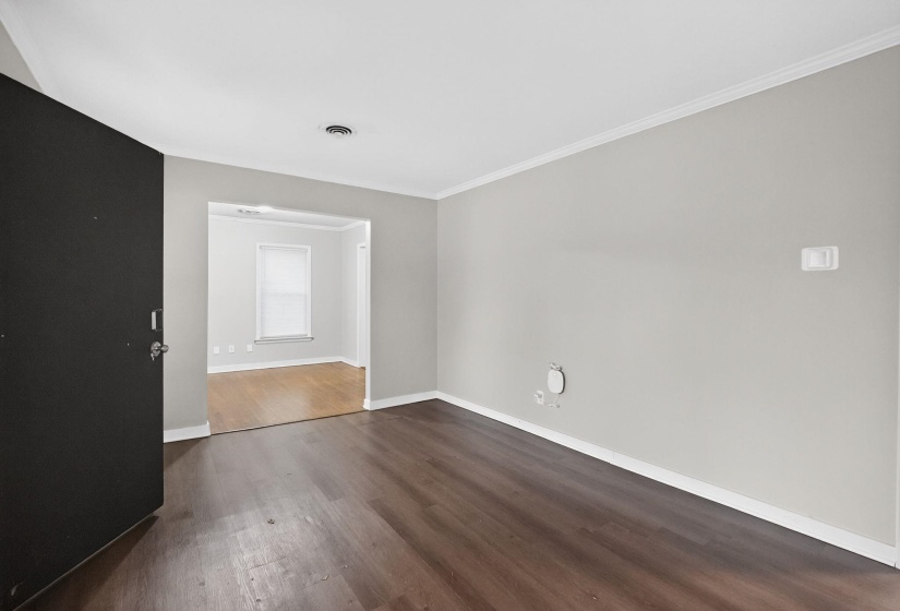 Empty room with dark wood finished floors and crown molding