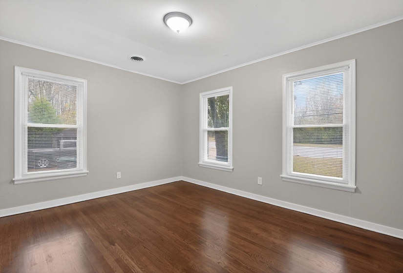 Empty room with ornamental molding, dark wood-style flooring, and plenty of natural light