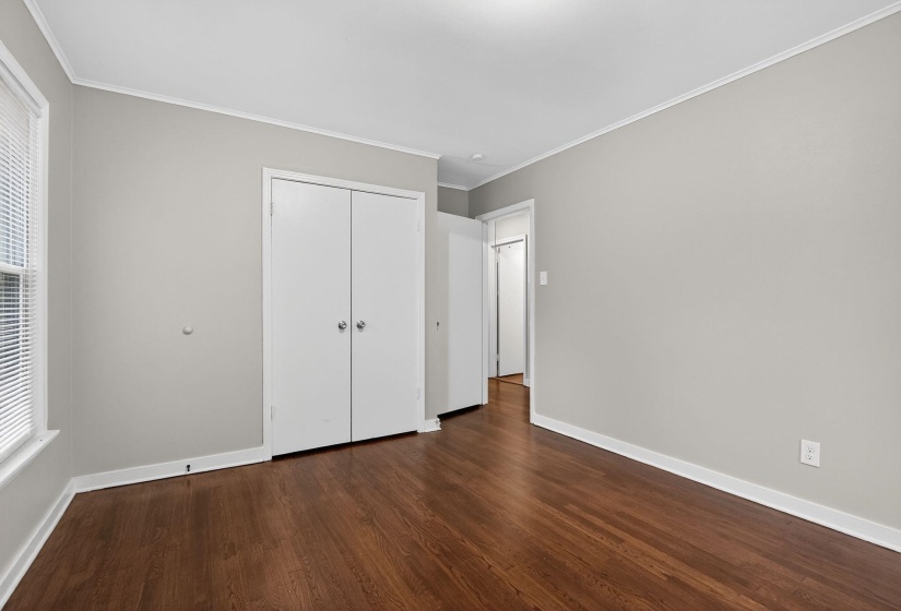 Unfurnished bedroom with ornamental molding, dark wood-style floors, and a closet