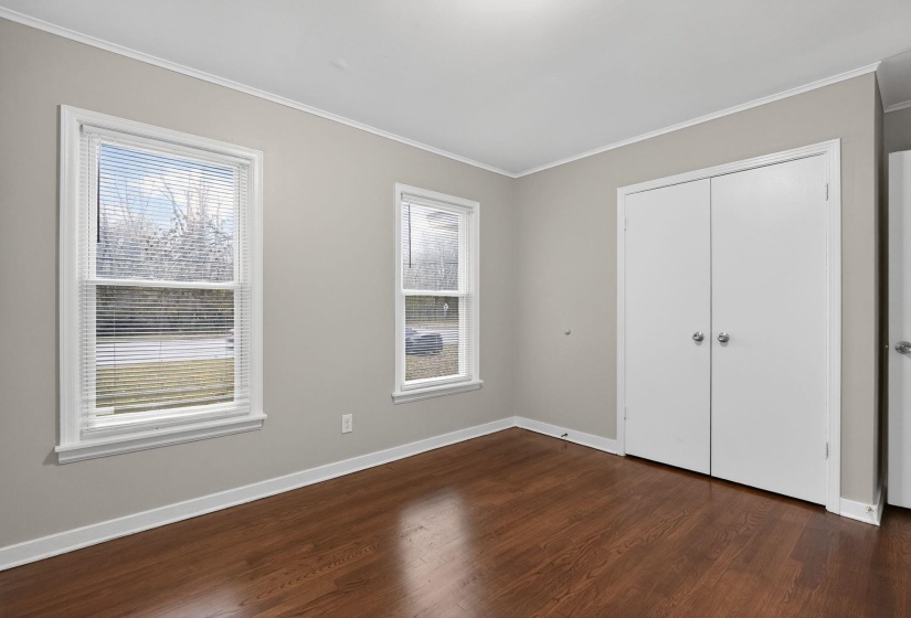 Unfurnished bedroom with ornamental molding, dark wood-style flooring, and a closet