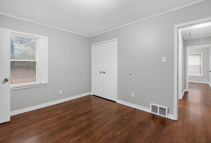 Unfurnished bedroom with attic access, dark wood-style flooring, a closet, and ornamental molding
