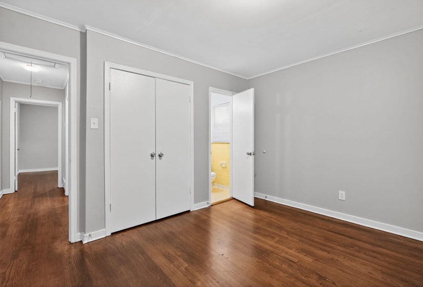 Unfurnished bedroom featuring attic access, ornamental molding, dark wood finished floors, and a closet