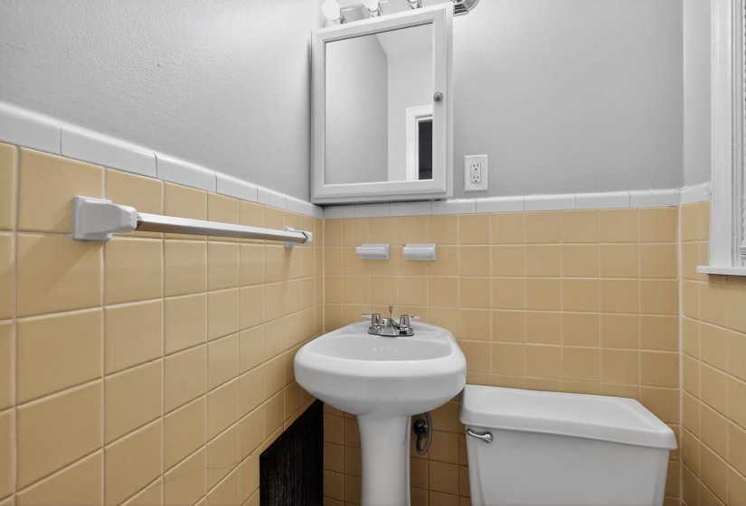 Half bathroom featuring wainscoting and tile walls