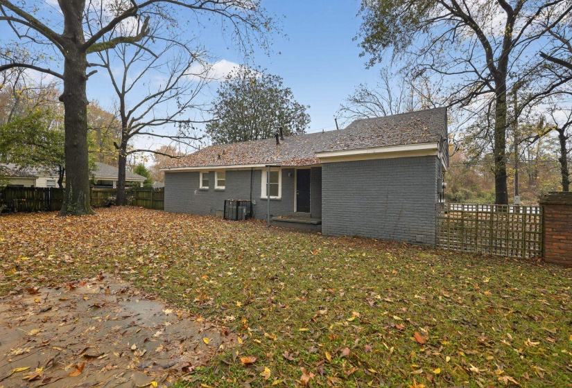 Back of property with a fenced backyard and brick siding