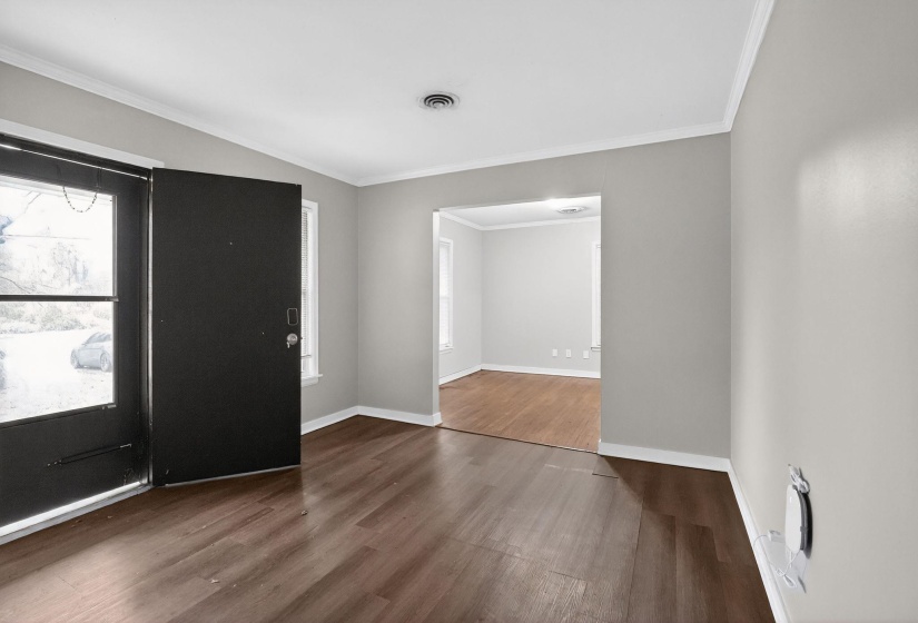 Foyer with ornamental molding and dark wood-style flooring