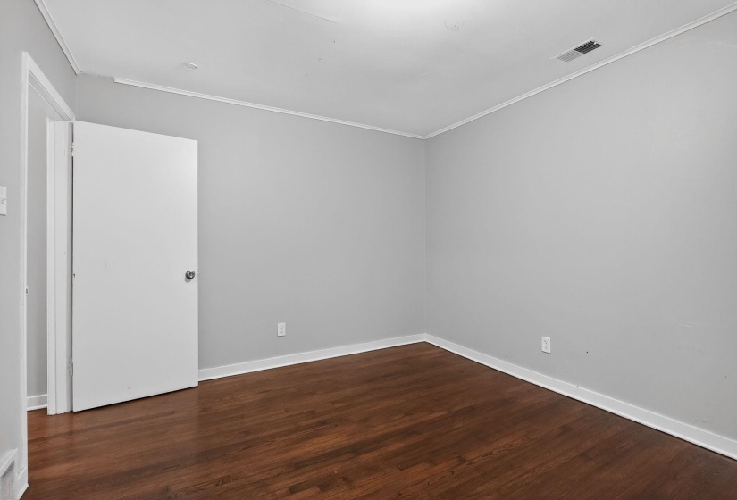 Spare room with dark wood-type flooring and ornamental molding