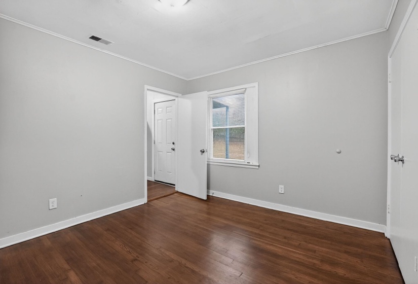 Unfurnished room with ornamental molding and dark wood-style flooring